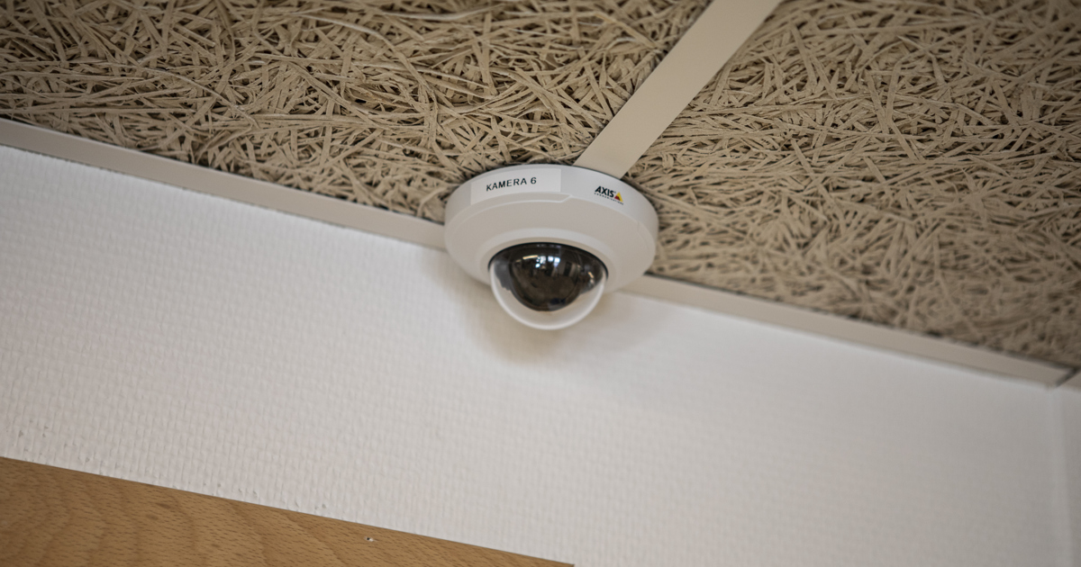 En övervakningskamera monterad i taket i ett rum.
