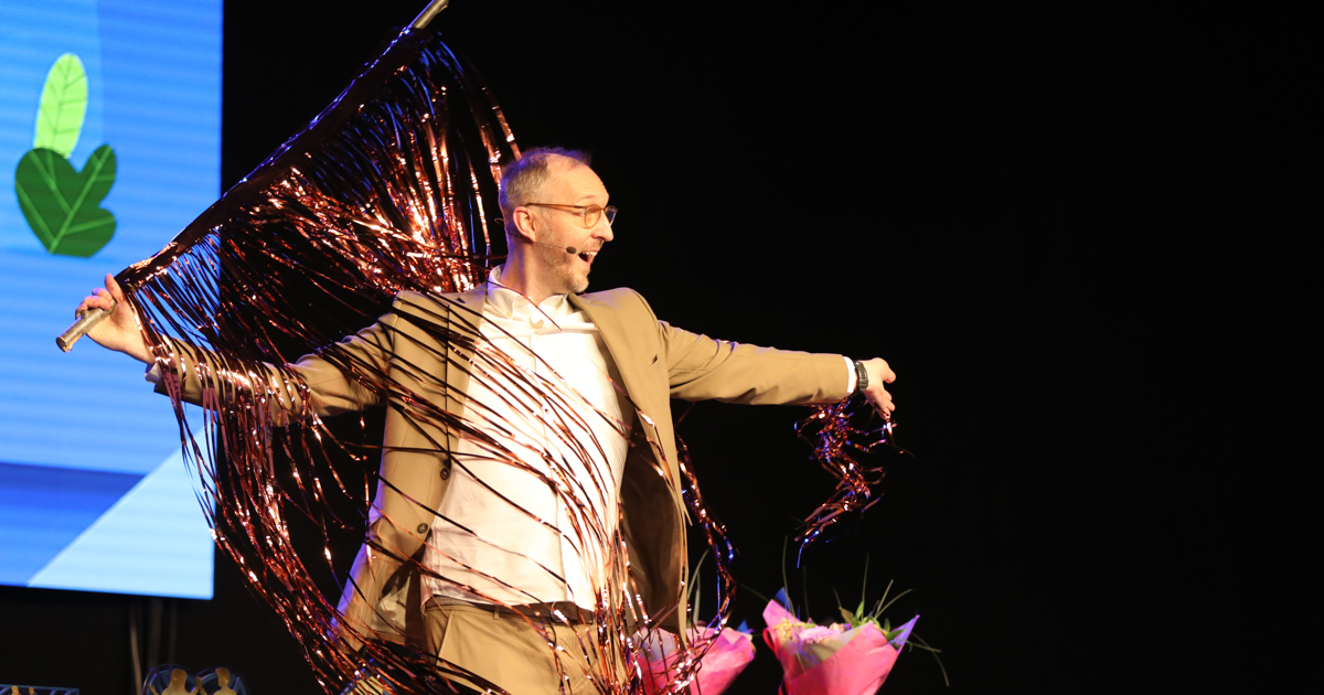 En man står på en scen med glittergardin.