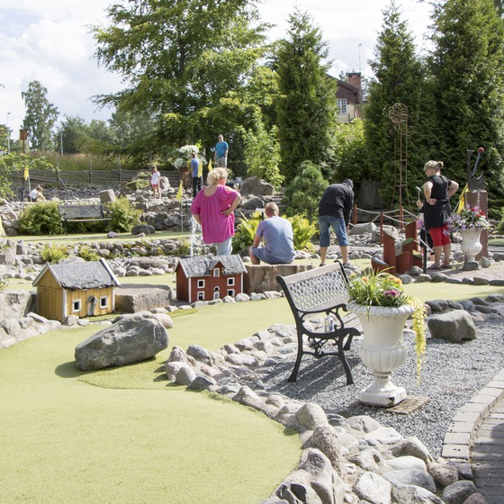 Äventyrsgolfbana med små hus och stenar som omgärdar banorna.
