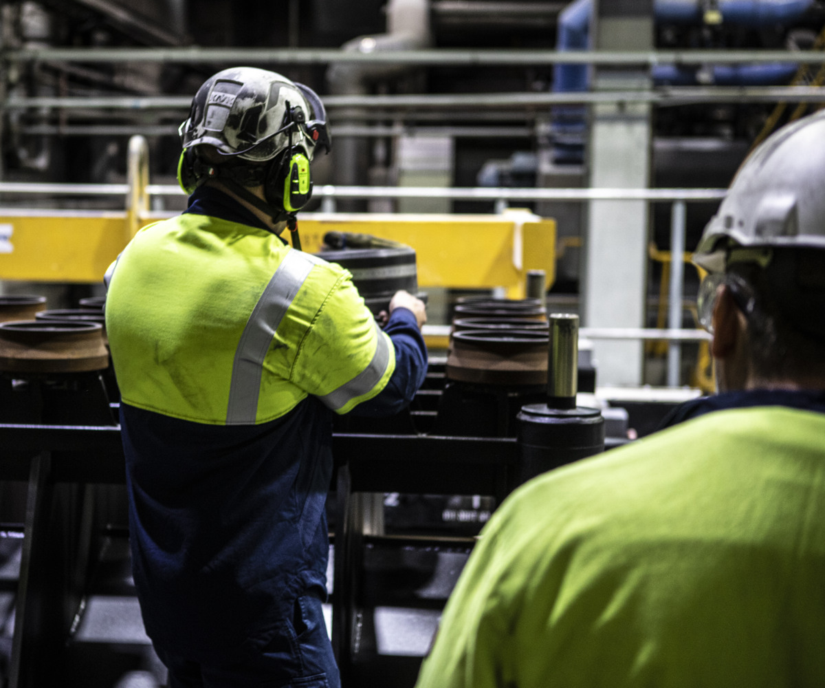 Två industriarbetare arbetar med stora gjutformar.