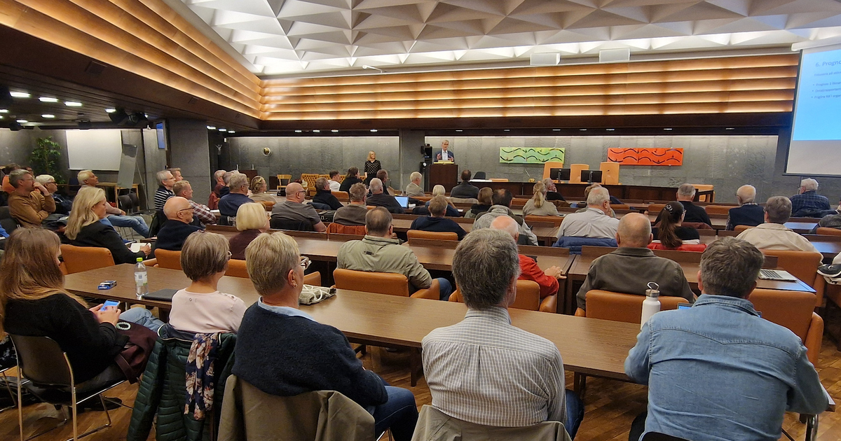 Möteslokal där personer sitter med ryggarna mot kameran.