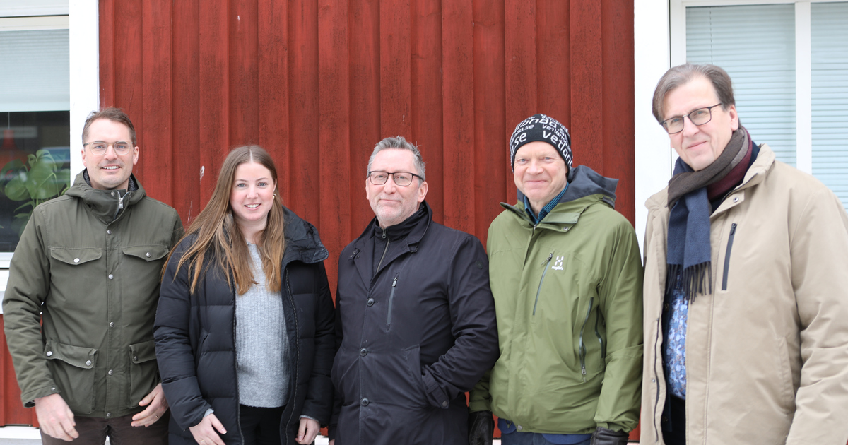 En grupp människor som står bredvid varandra framför ett rött hus.