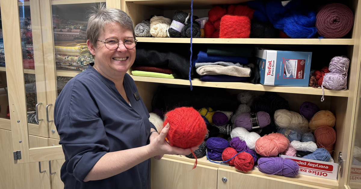 Slöjdlärare står vid skåp med garner och håller i ett nystan.