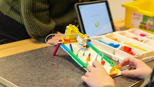 Ett barn bygger med lego och programmerar på en surfplatta